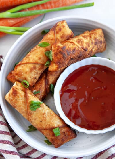 Egg rolls in a dish with dipping sauce.