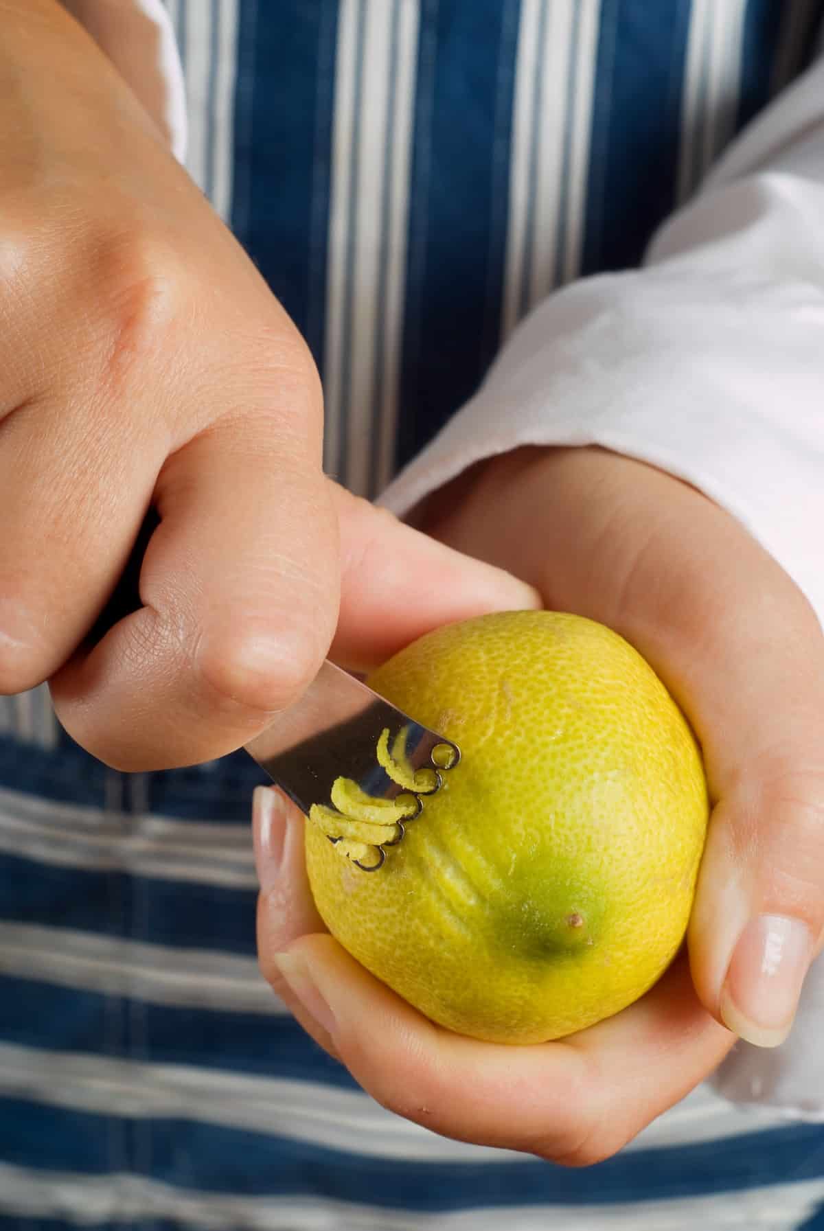 Female woman cook or chef cutting or zesting a lemon.