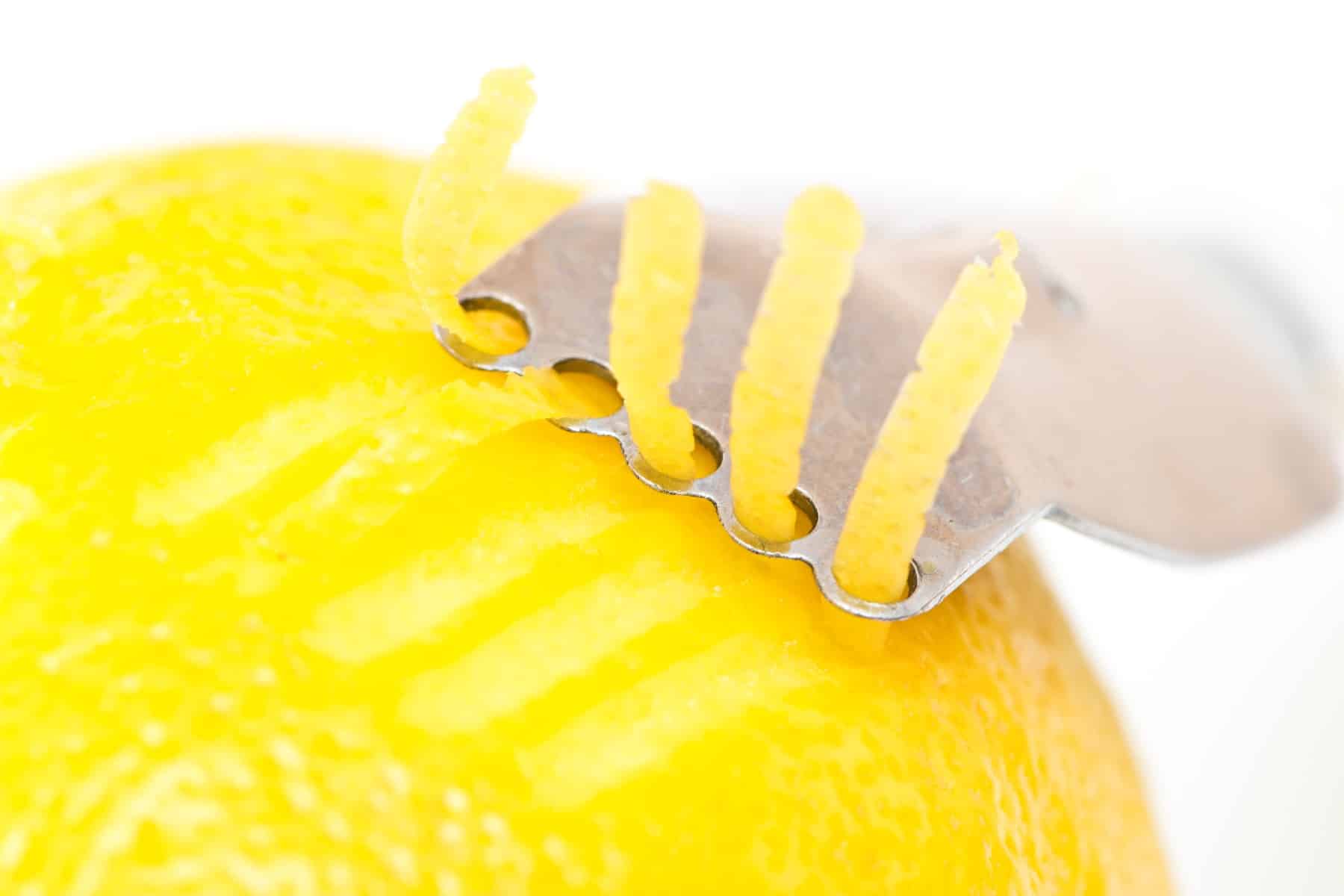 Lemon peel on white background being zested. 