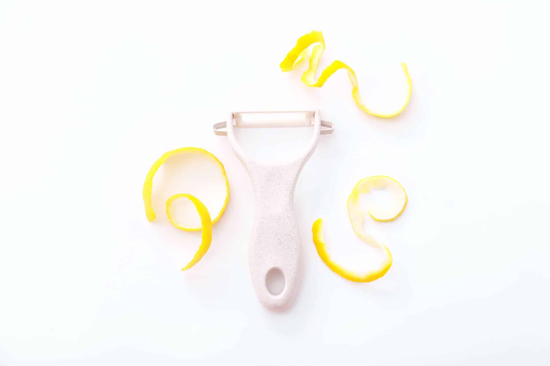 Lemon zest with zester on a white background.