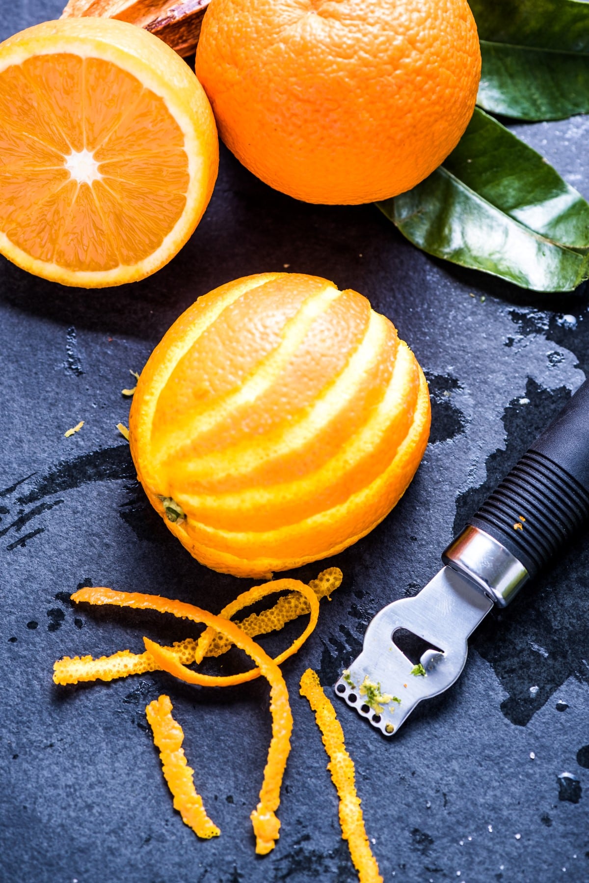 Orange and zest, natural refreshing ingredients on dark slate.