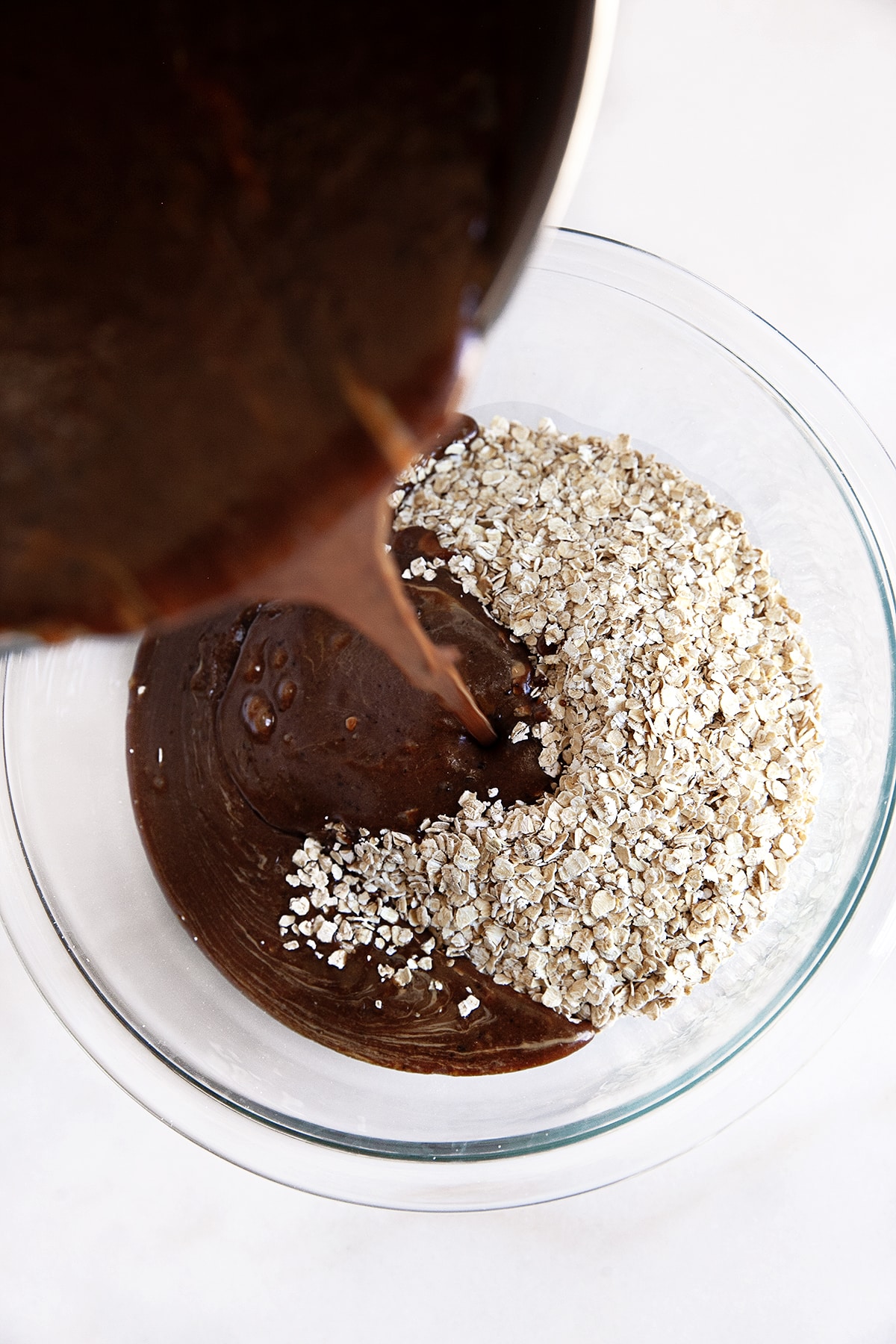 Pouring chocolate mixture into oats. 