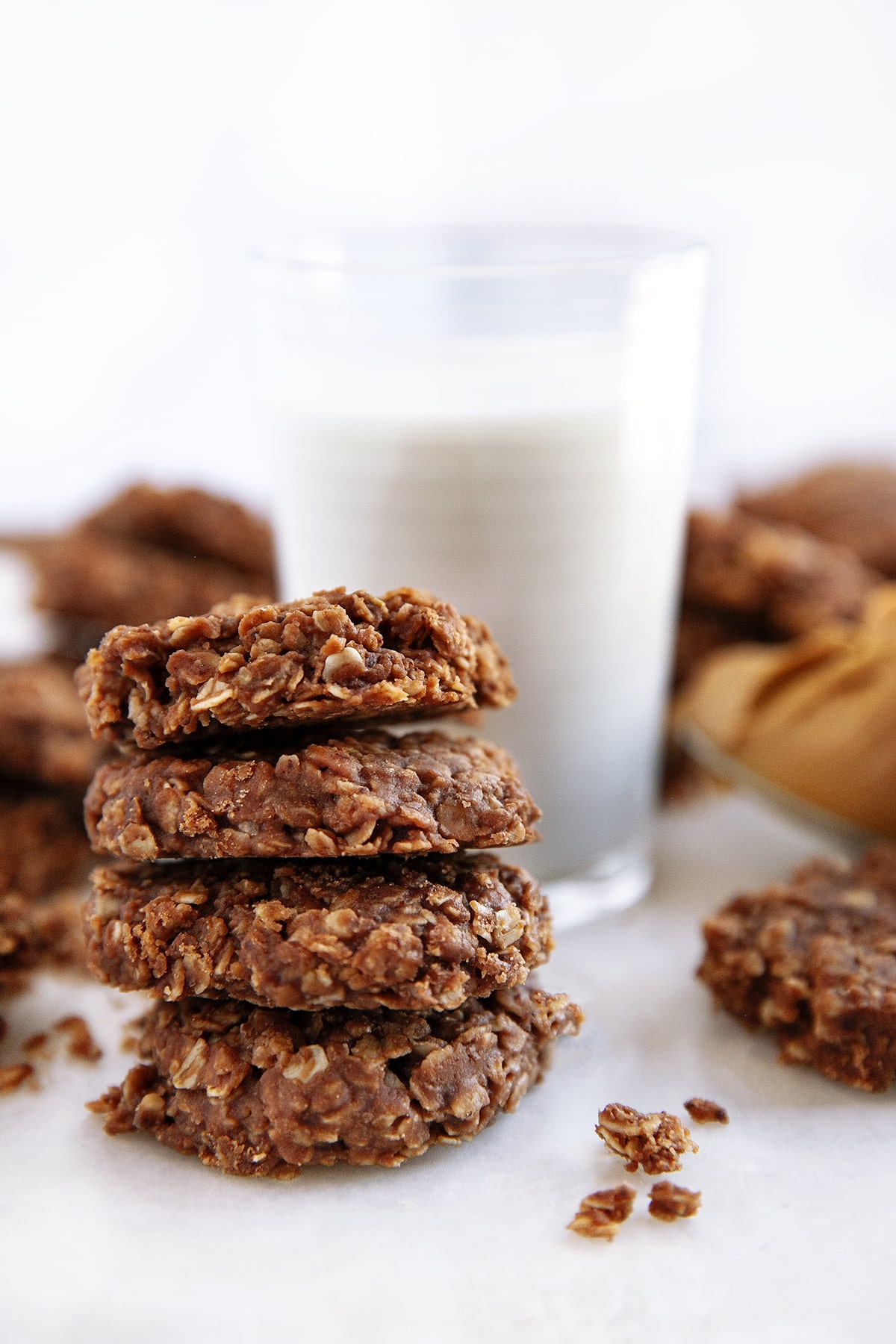 Four cookies stacked in front of a glass of milk. 