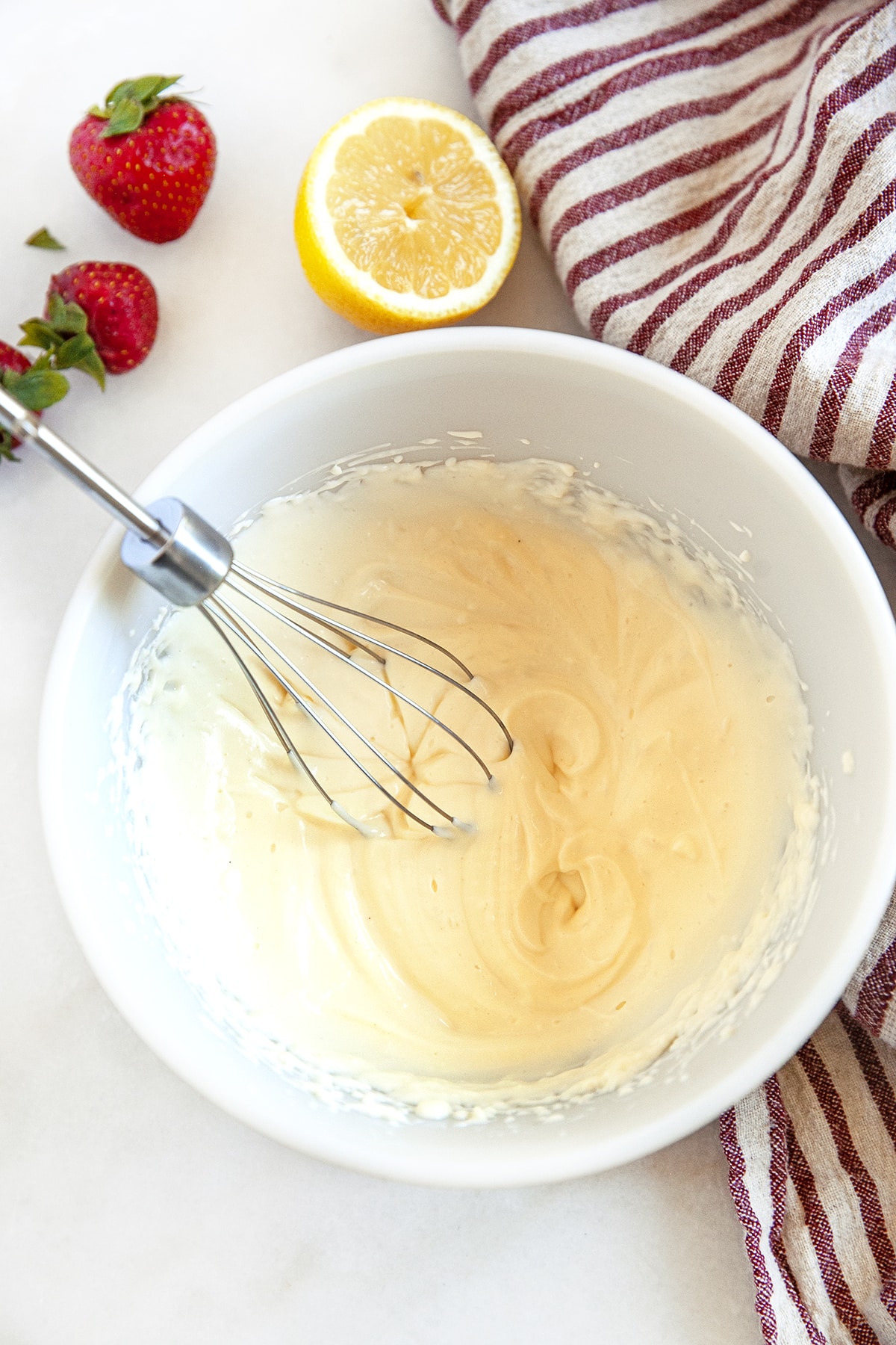 Cream cheese filling in a bowl with a whisk. 