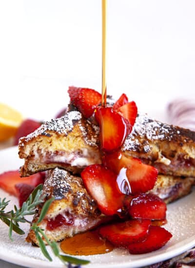 Pouring maple syrup over stuffed French Toast with strawberries.