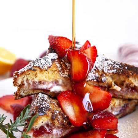 Pouring maple syrup over stuffed French Toast with strawberries.