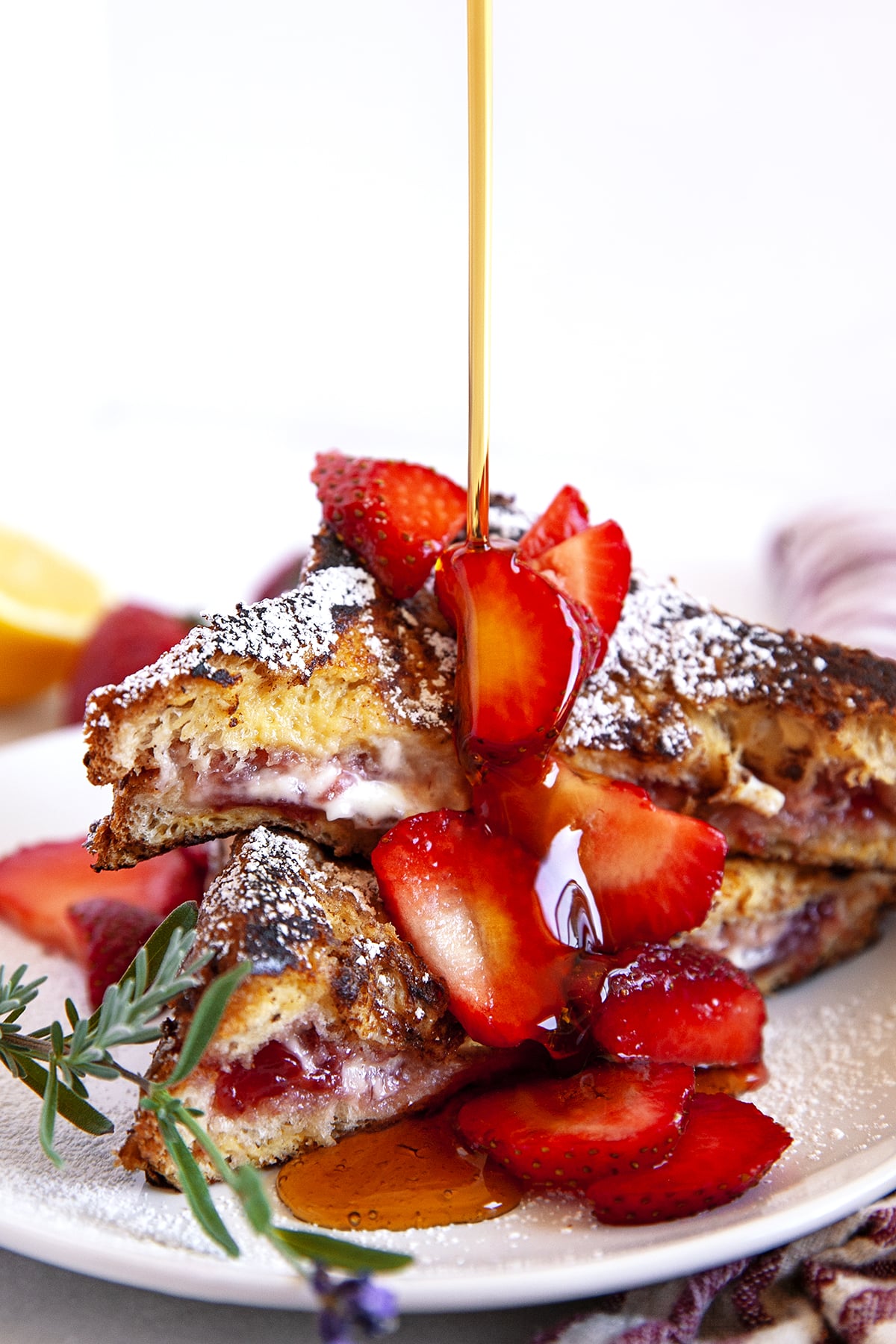 Pouring maple syrup on stuffed French toast topped with strawberries. 