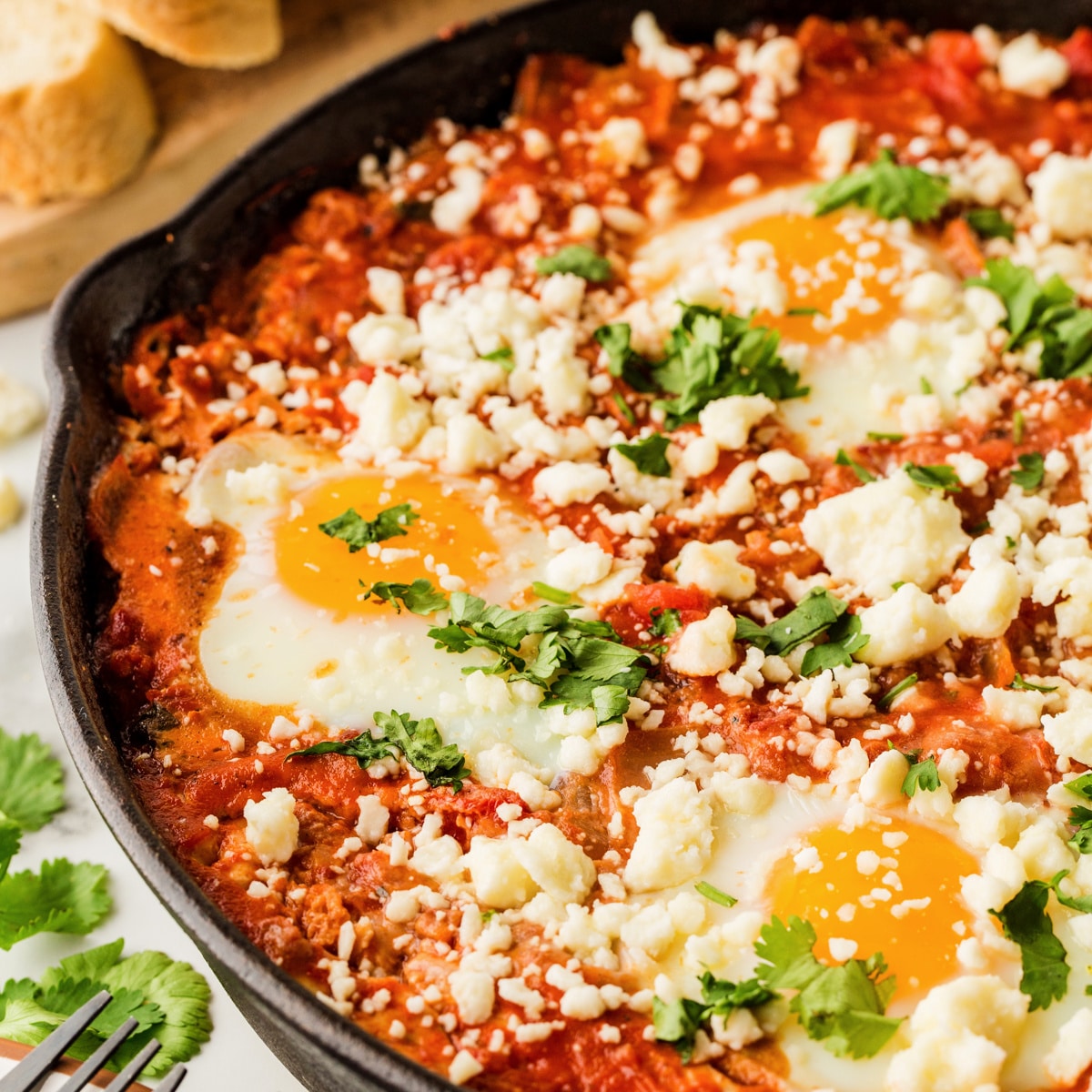 Square photo of shakshuka in a cast iron pan. 