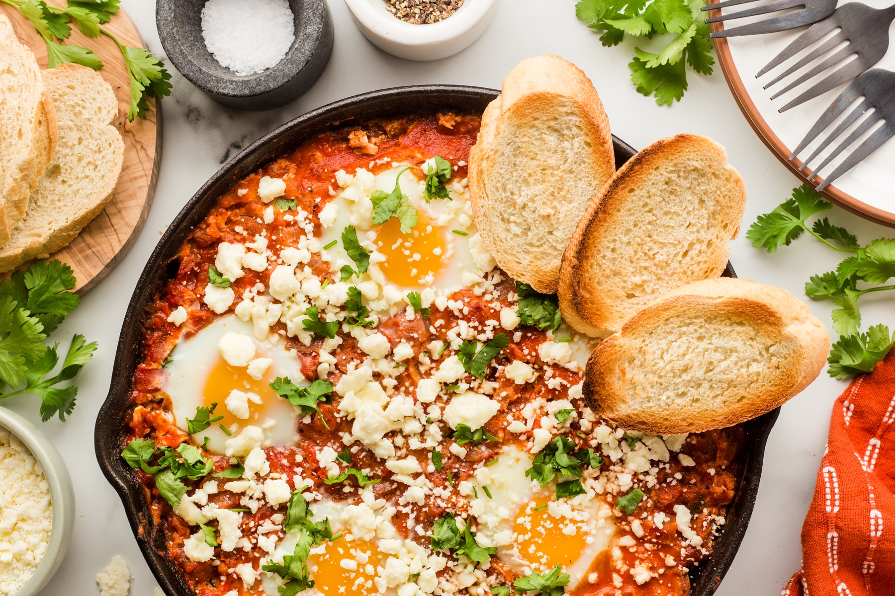 Horizontal photo of shakshuka with toasts in a cast iron pan. 