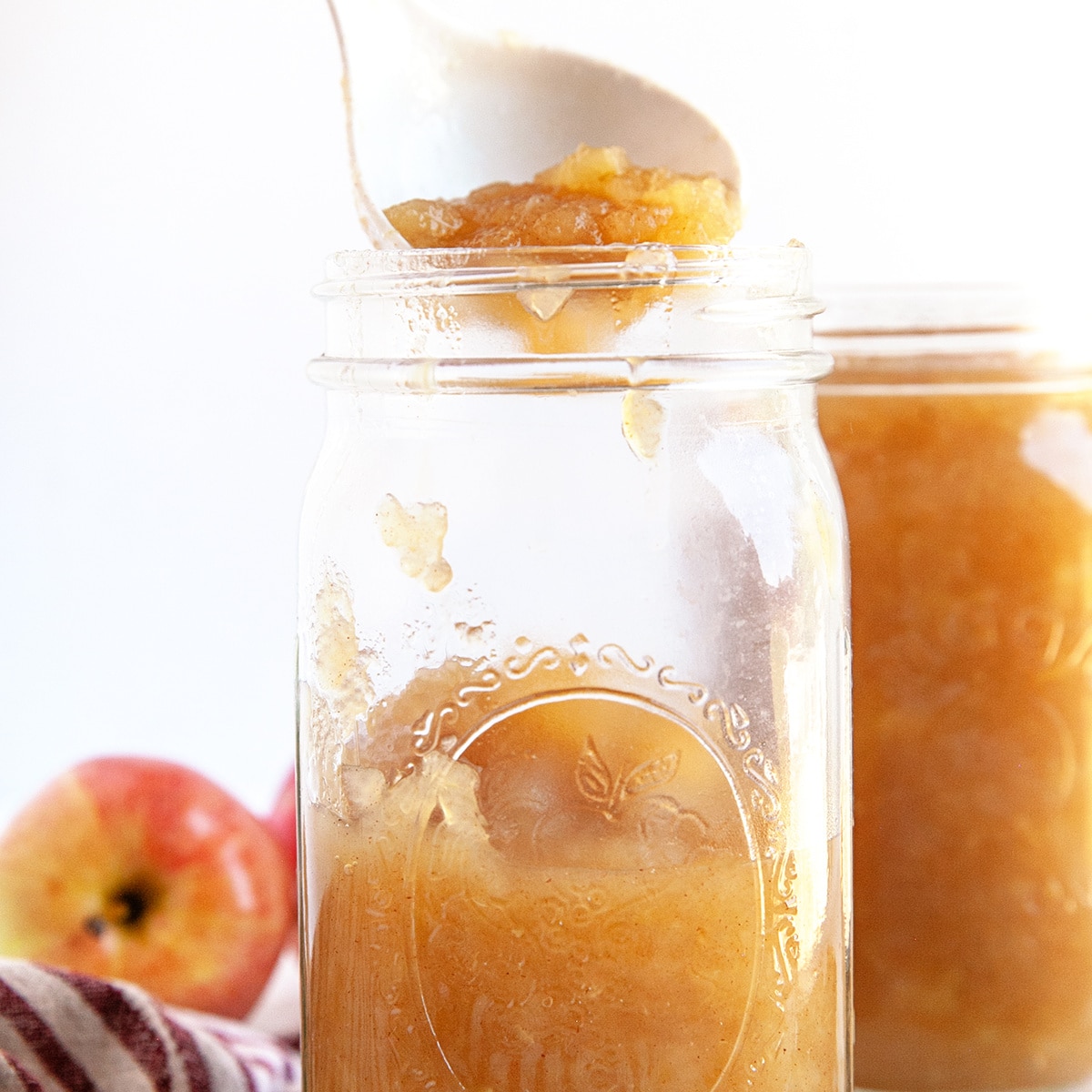 Square photo of putting apple sauce in to jars. 
