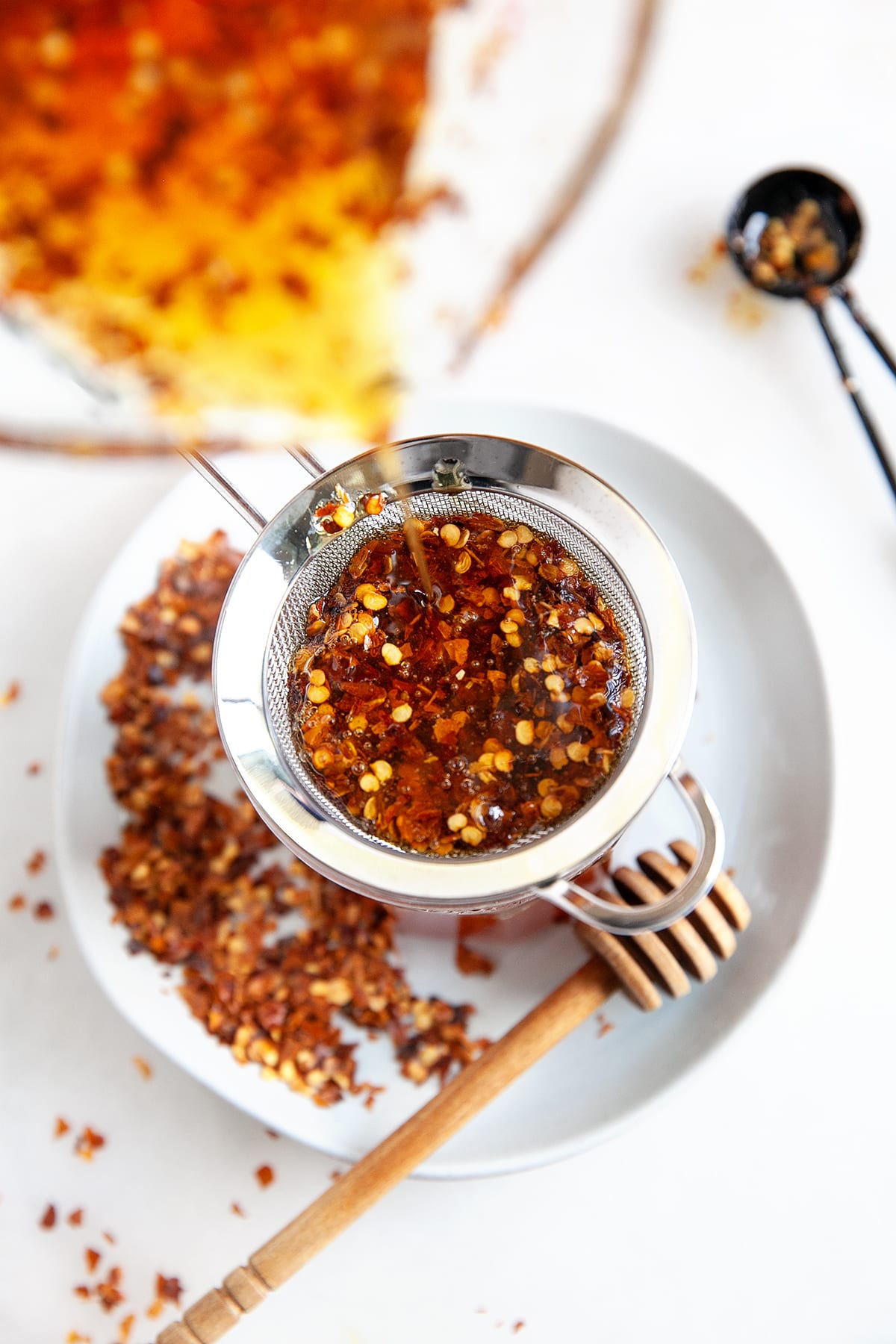 Showing honey being strained through a small sieve. 