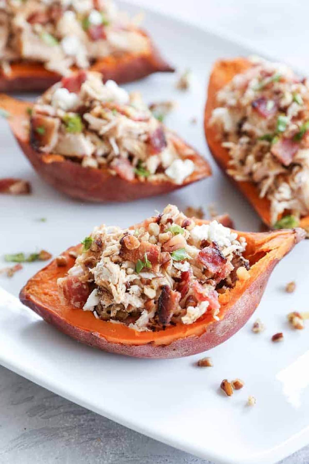 Loaded Sweet Potato Skins with Pecans, Chicken, and Bacon on a white platter.