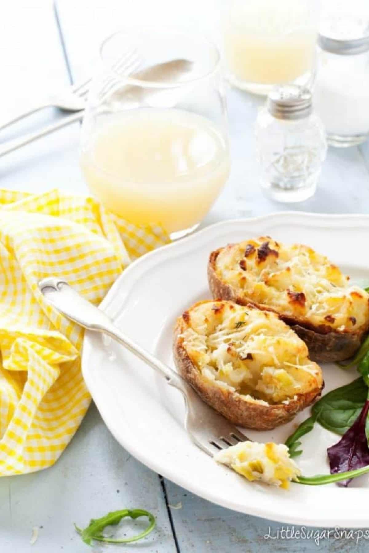 Cheesy Leek Baked Potatoes on a white plate with a fork and salad.