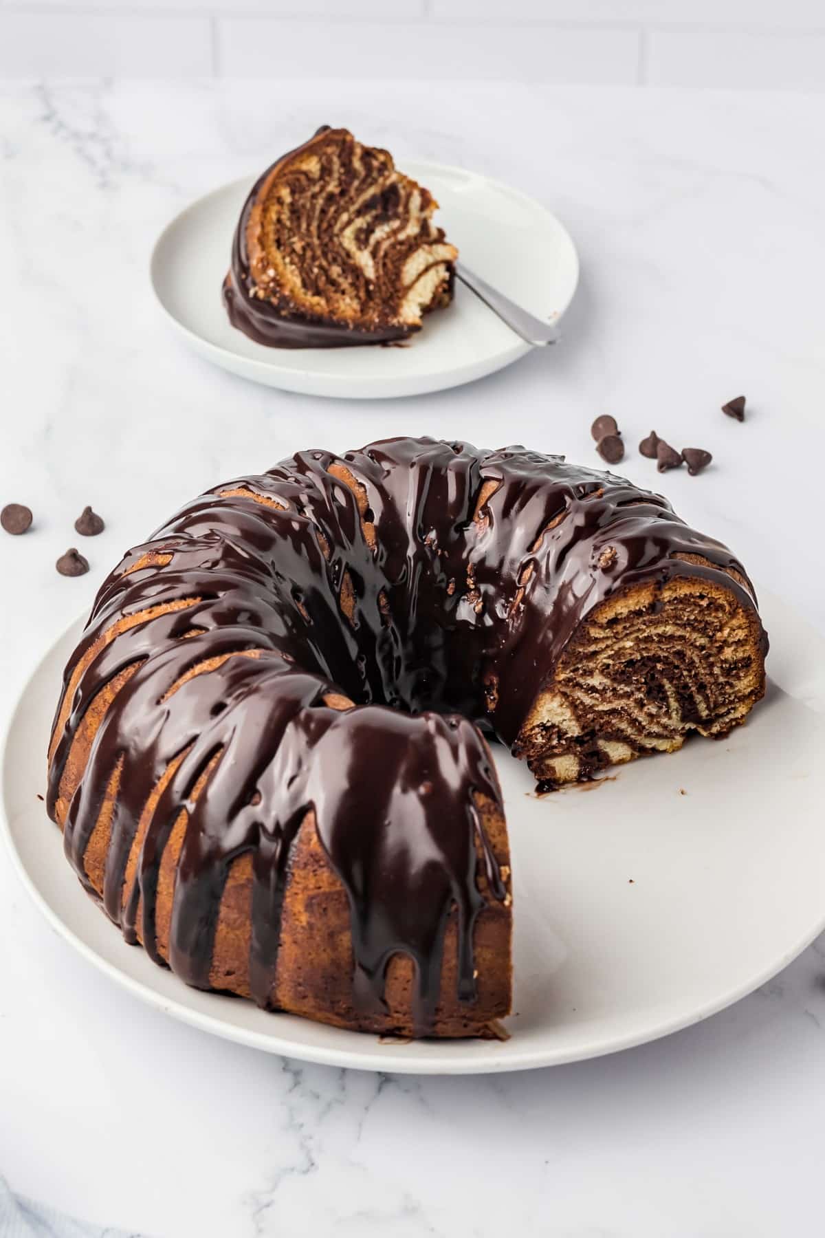 Partially sliced bundt with a slice on a plate in the rear. 