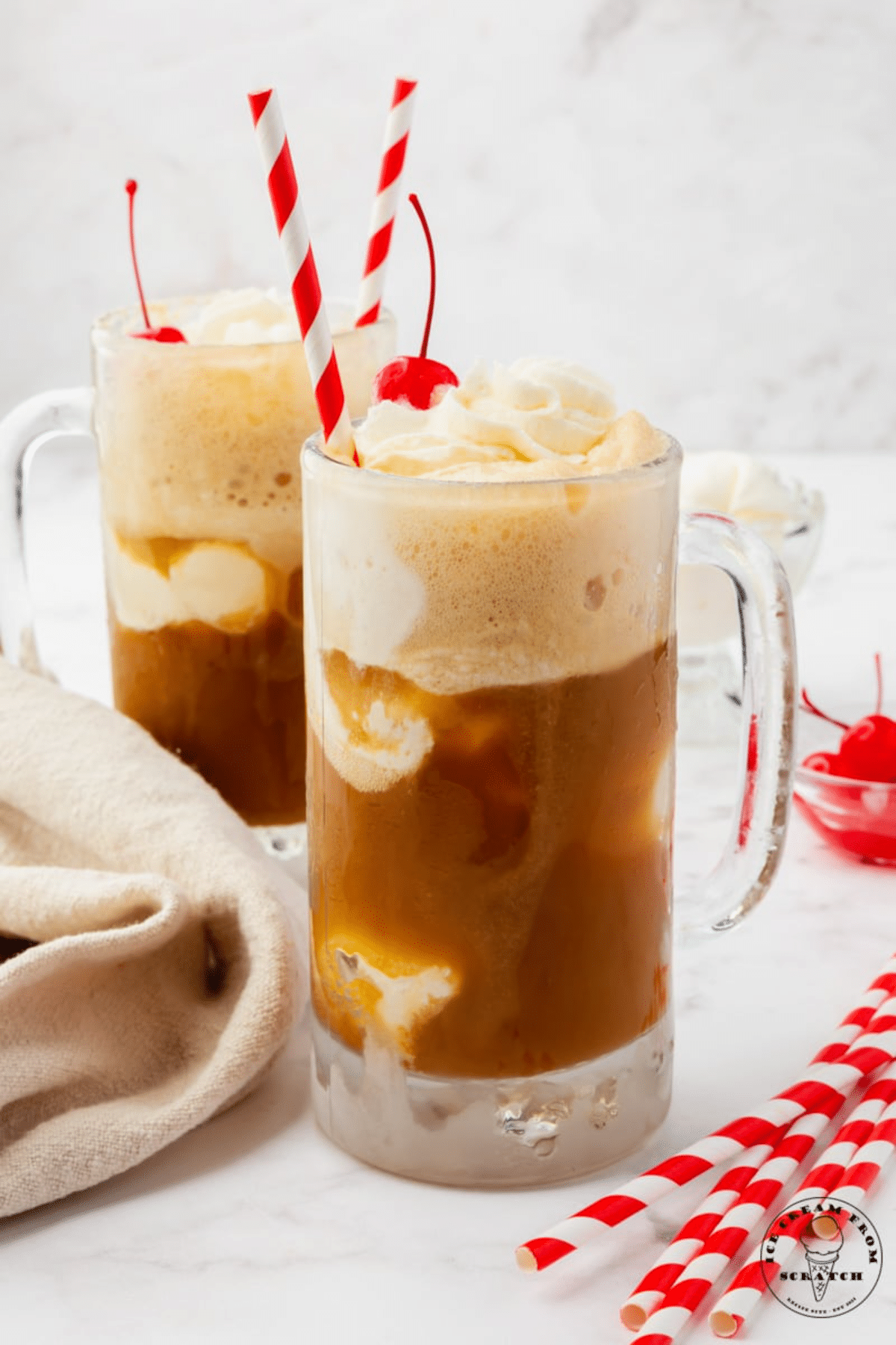 Root beer float with red and white striped straw and a cherry on top. 