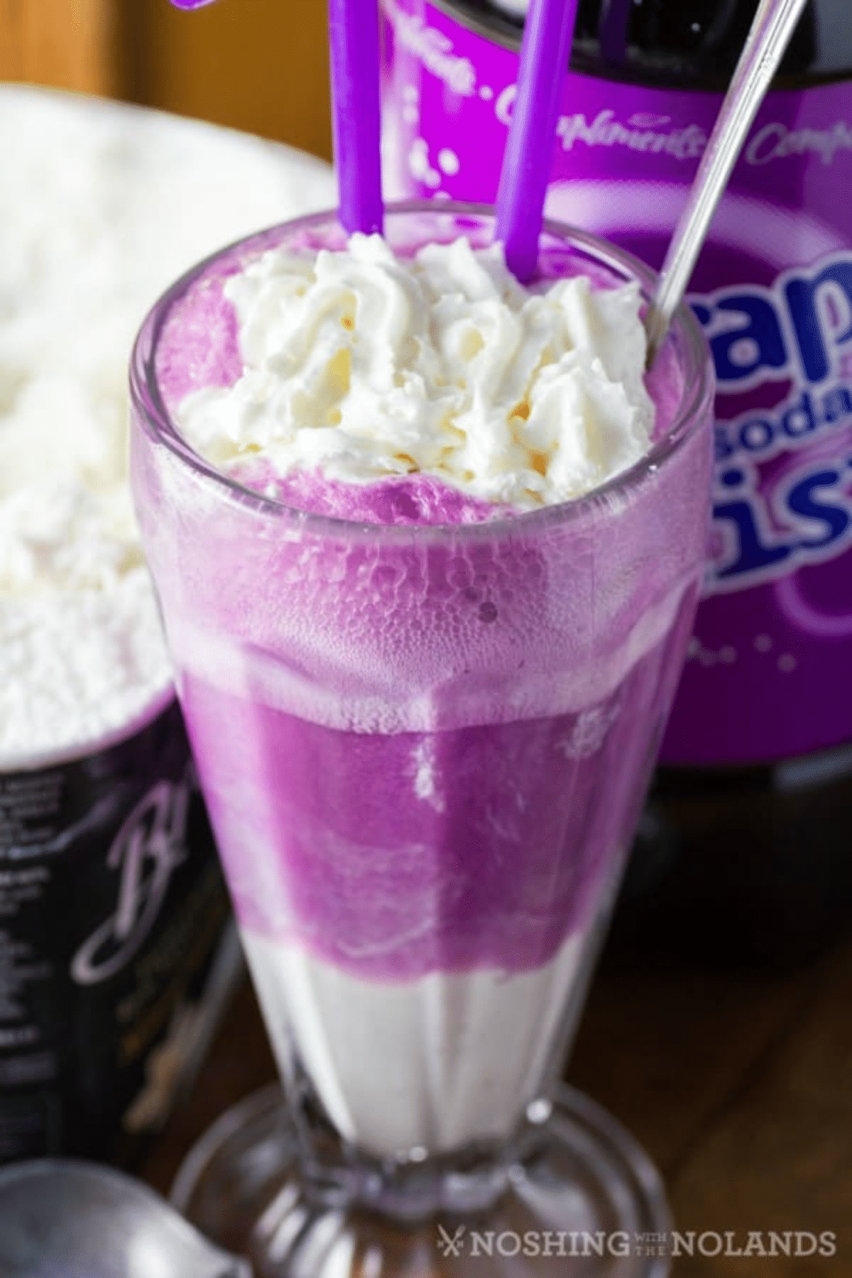 Grape Ice Cream Float in a tall glass with a spoon and purple straws. 