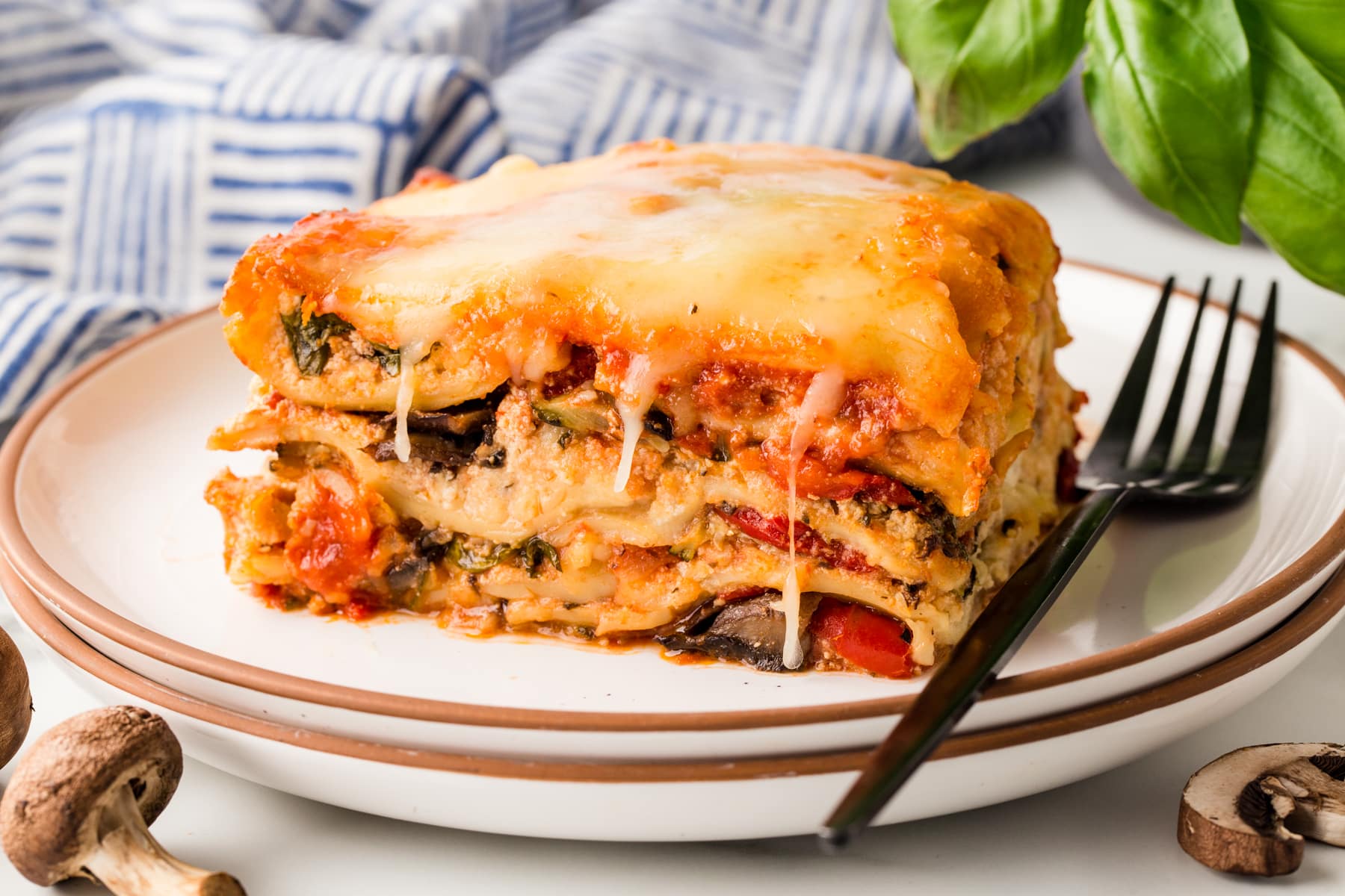 Horizontal picture of vegetable lasagna on a plate with a black fork. 