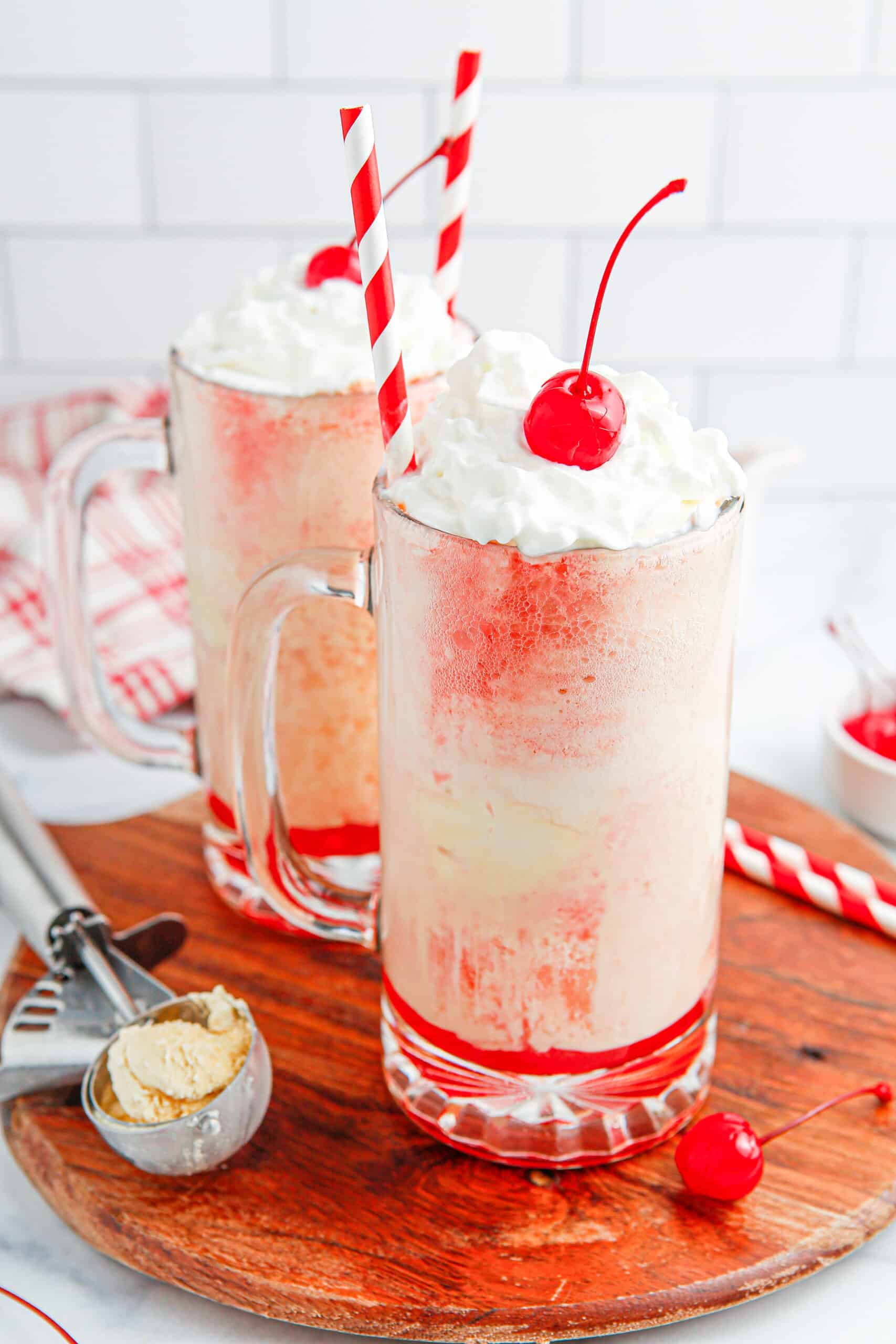 Cherry Float with whipped cream and cherry and a red and white straw. 