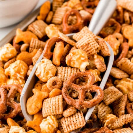Taking a scoop of Homemade Chex Mix off a tray.
