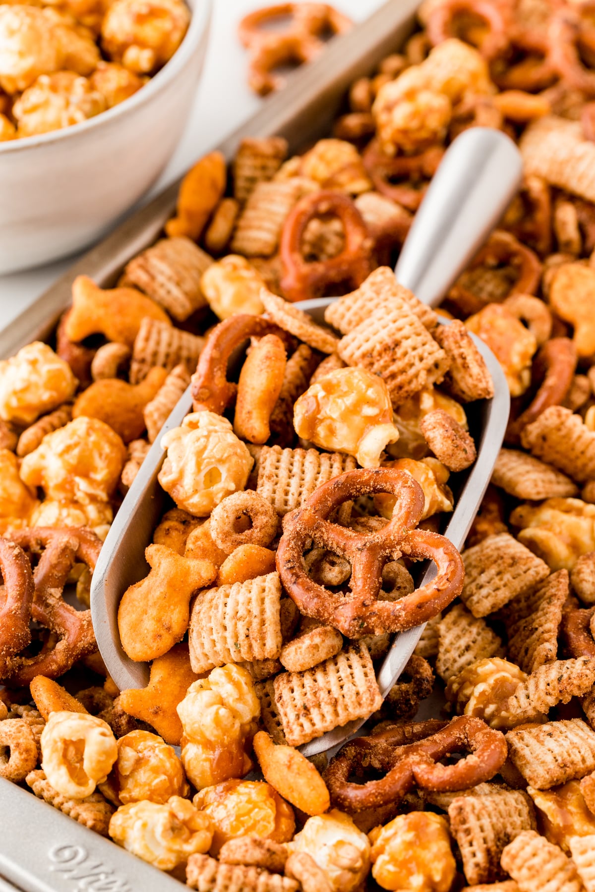 Taking a scoop of Homemade Chex Mix off a tray.