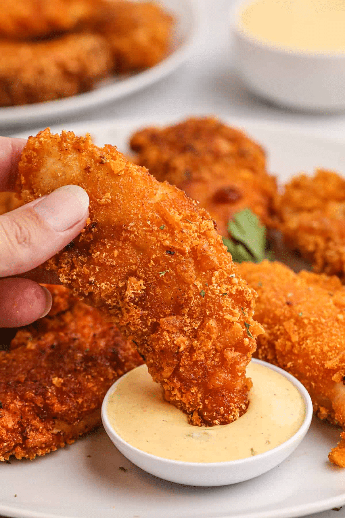 Captain Crunch Chicken Fingers being dunked in a mustard sauce. 