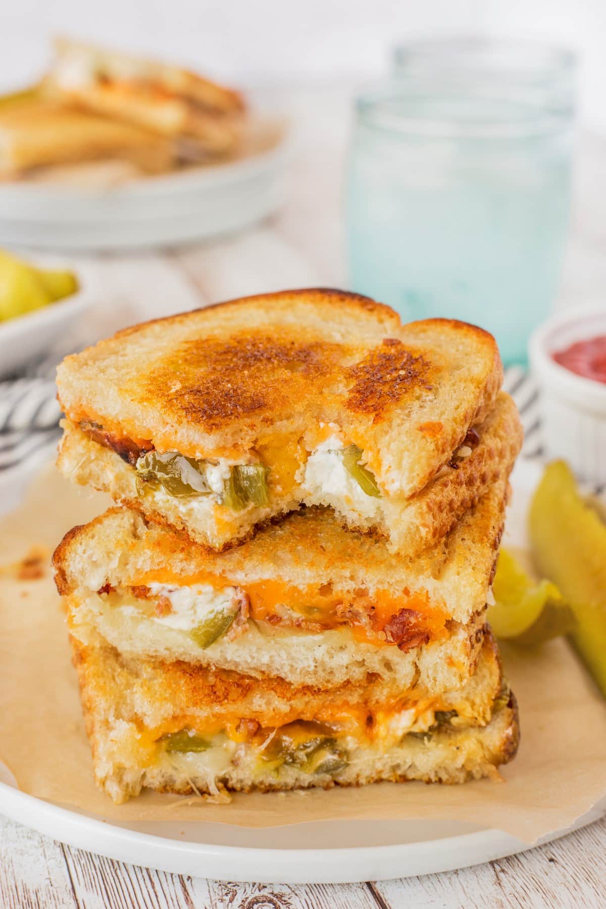 Close-up of a jalapeno popper sandwich stacked with the top sandwich with a bite taken. 