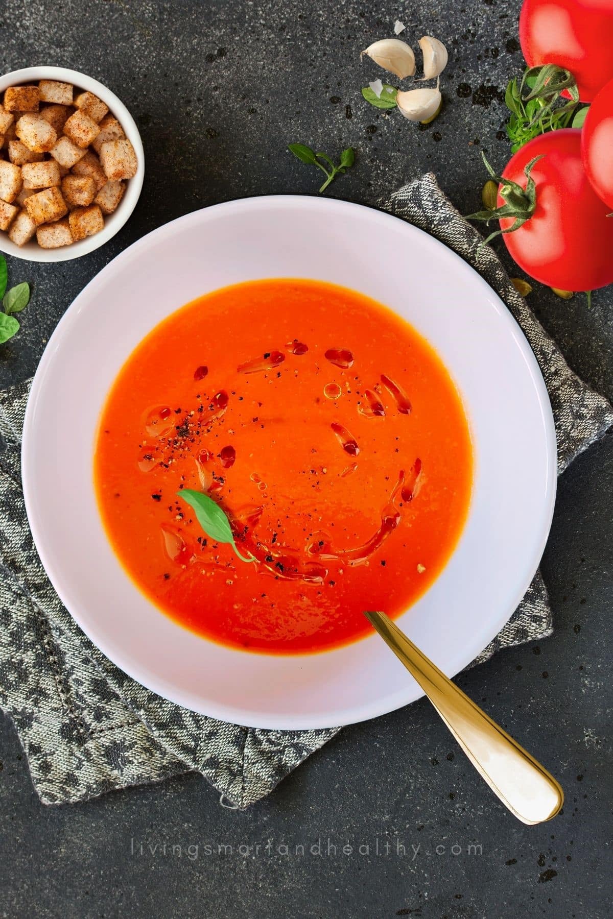 Roasted Red Pepper Tomato Soup taken from overhead in a white bowl with a gold spoon. 