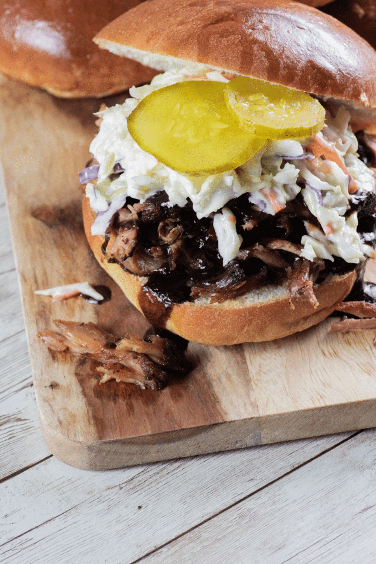 Pulled pork sandwich with slaw and pickles on top. 