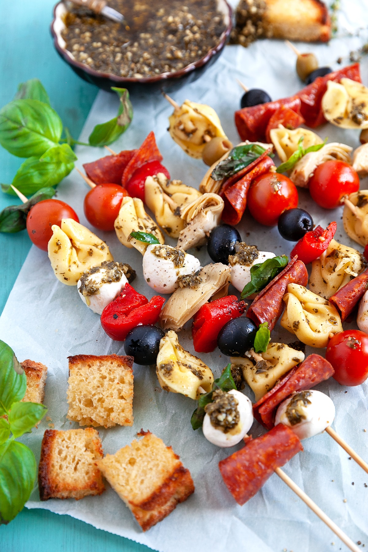 Appetizer Tortellini Skewers on parchment with toasted bread cubes. 