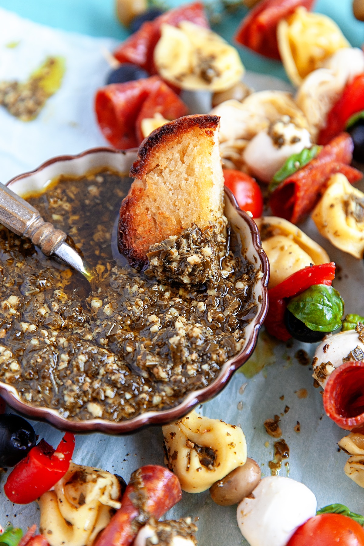 Dipping a toasted bread chunk in pesto. 