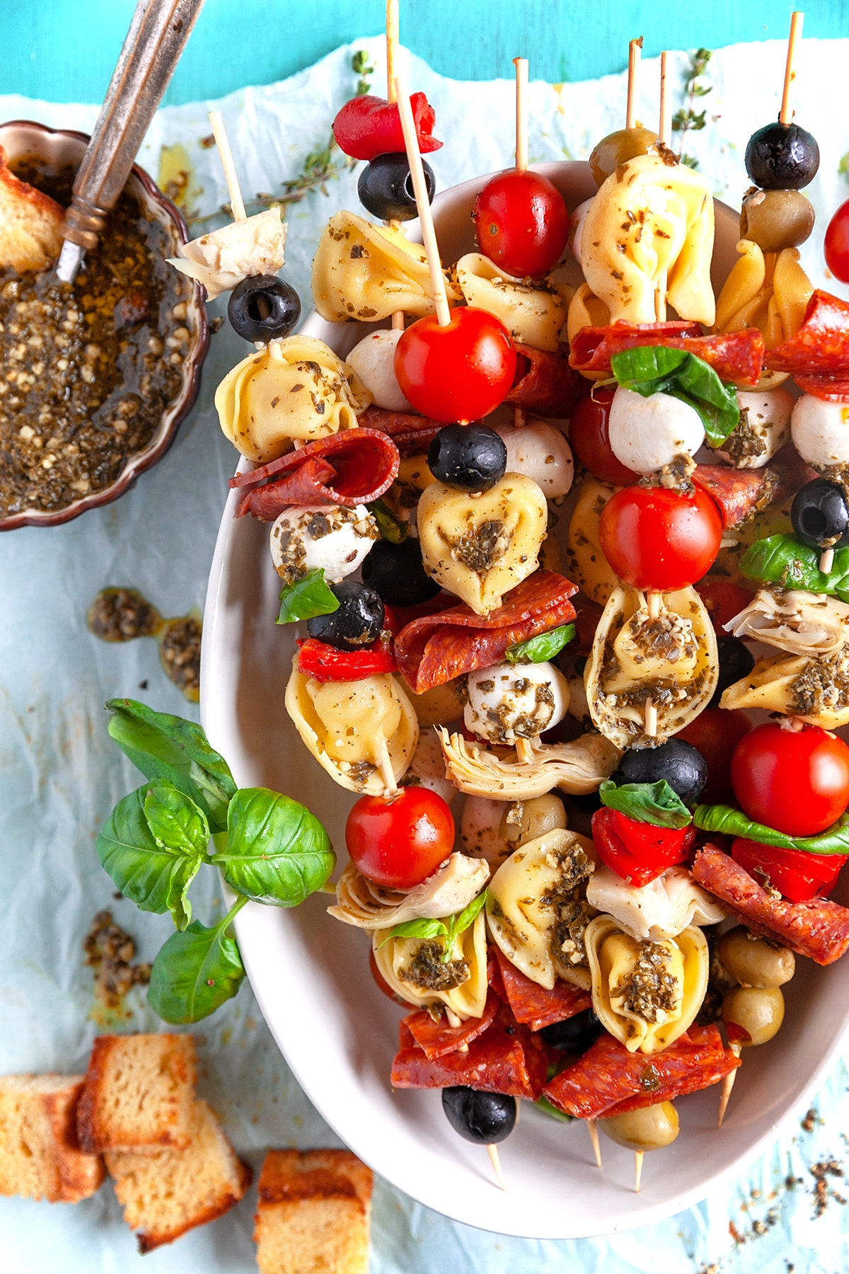 Overhead shot of Appetizer Tortellini Skewers in a white dish with extra pesto. 