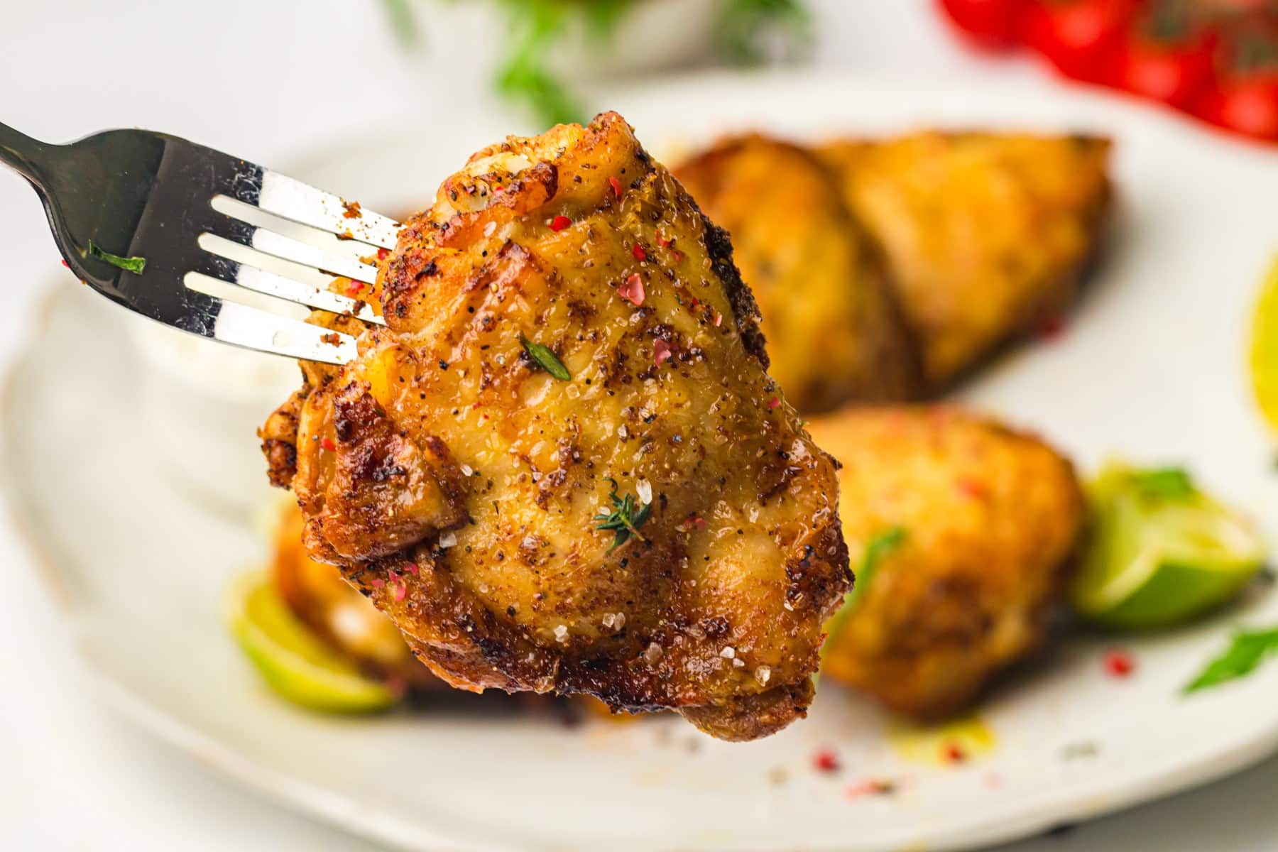 Horizontal shot of cooked air fryer chicken thigh on a fork.