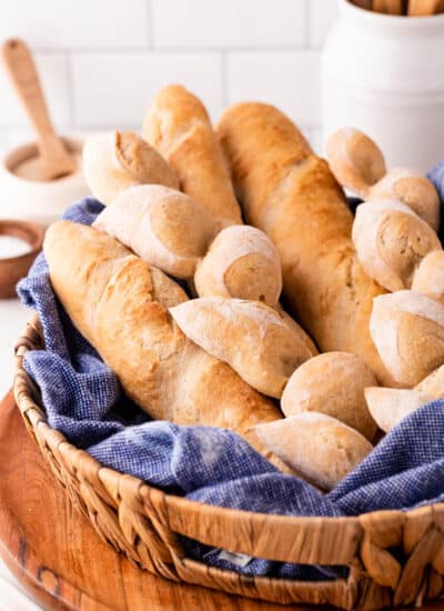 Epi and baguettes in a basket with a blue tea towel.