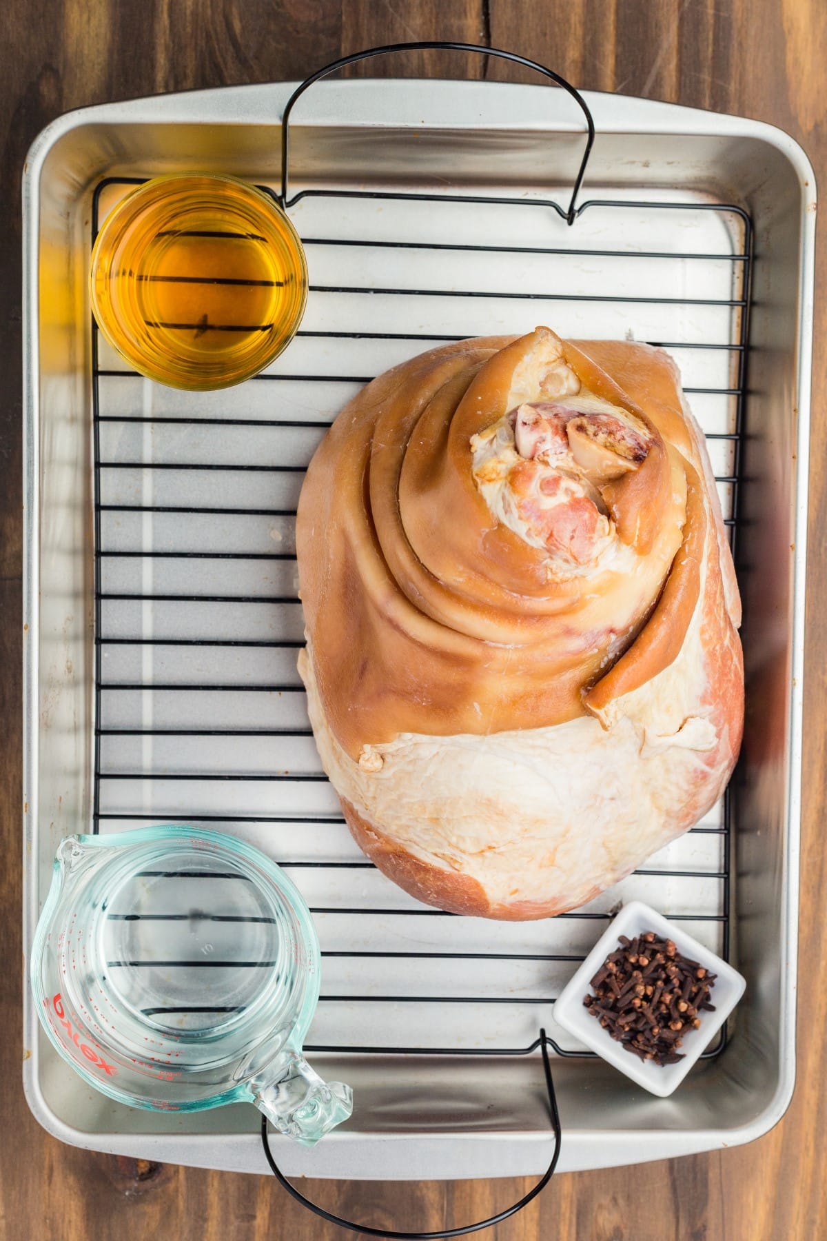 Ham, water, juice and cloves in a roasting pan. 