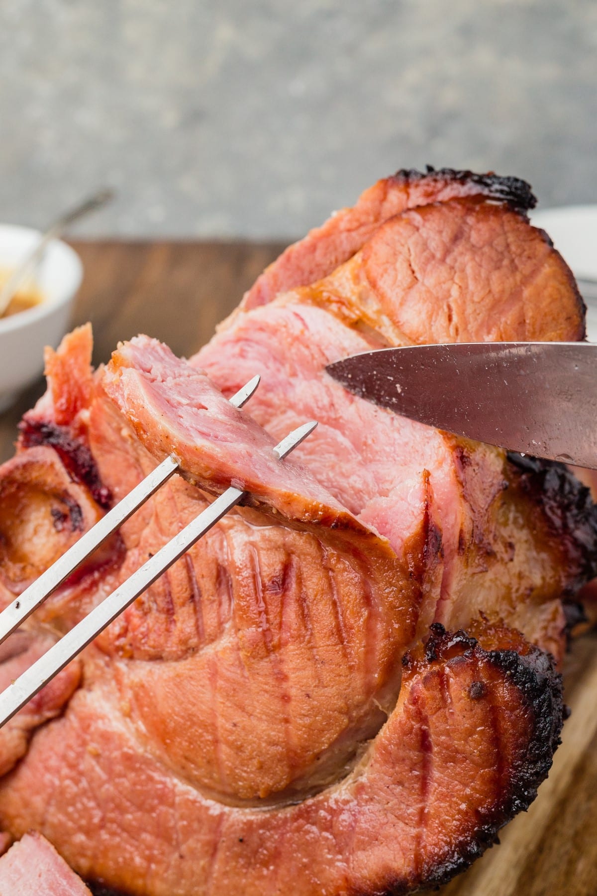 Slicing ham with a knife and two prong fork. 