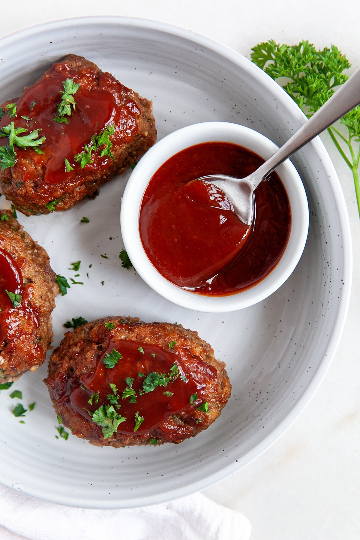 Overhead of mini meatloaves with a bowl of sauce. 