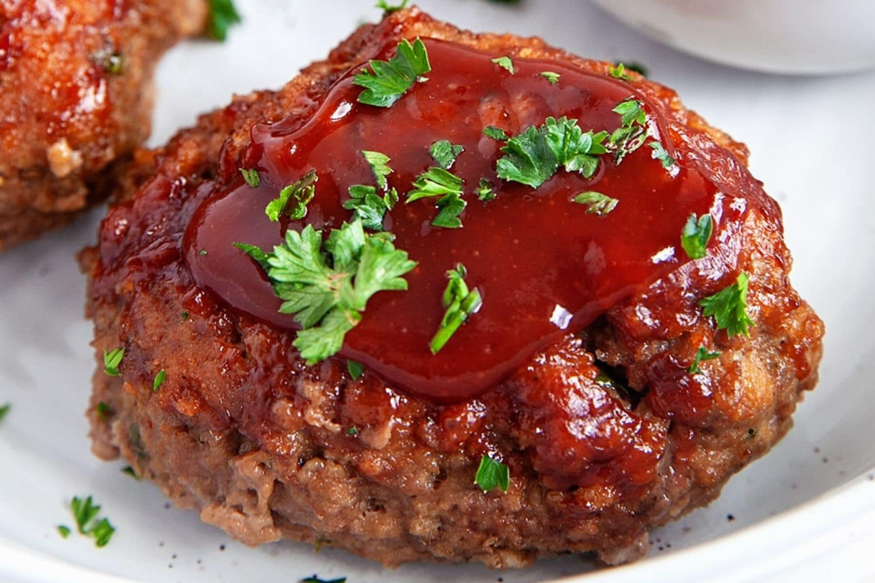 This little Mini Meatloaf Recipe will be a hit with the family. They are like a traditional meatloaf served up in cute little portions. Close-up of one mini meatloaf.