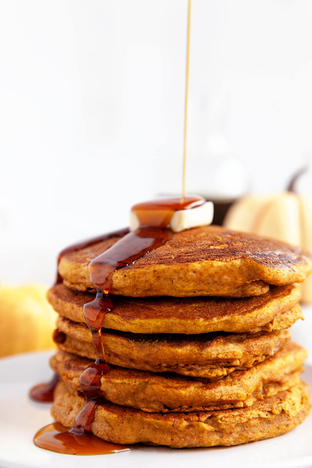 Pouring the syrup over a stack of pumpkin pancakes.