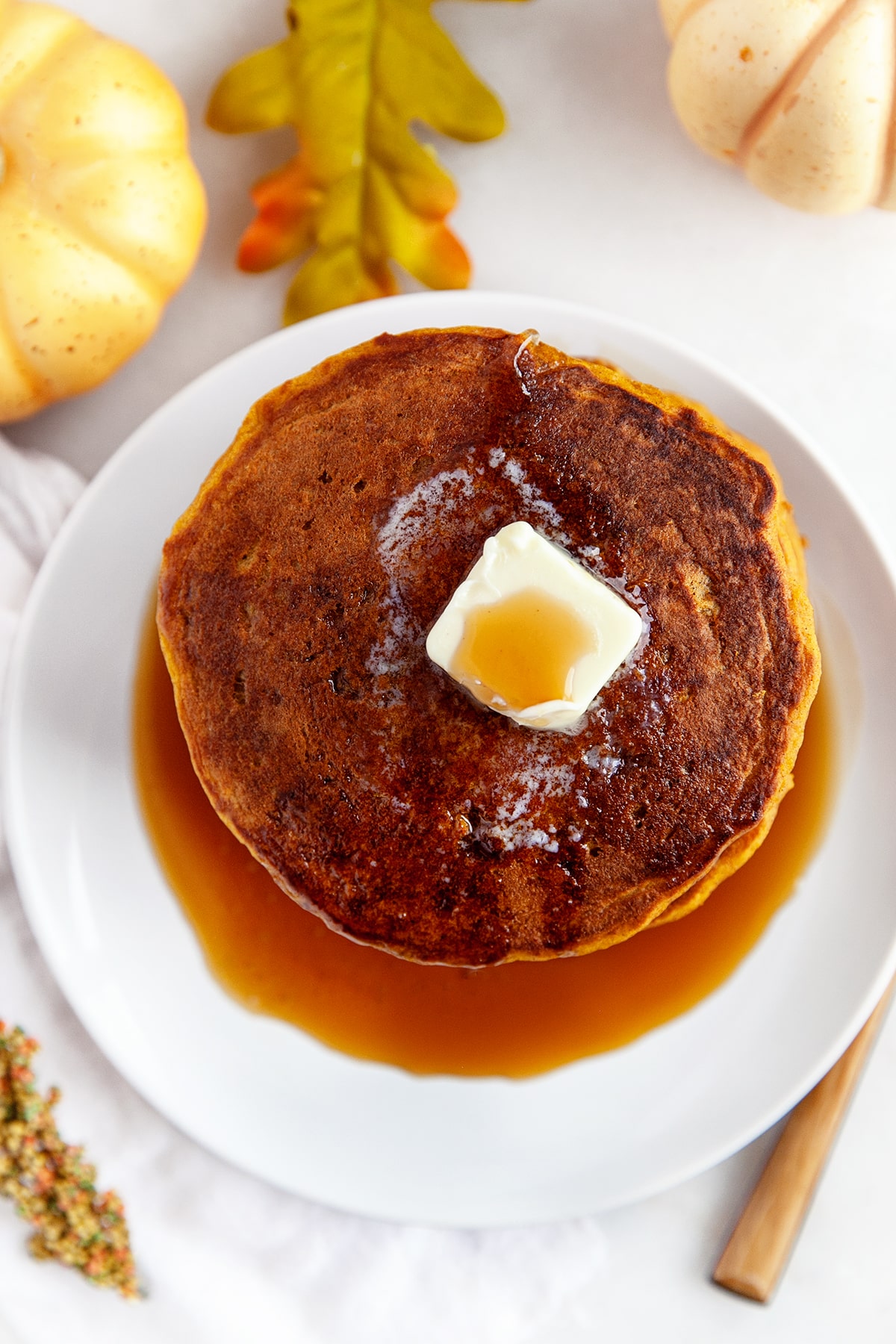 Overhead shot of pumpkin pancakes in a stack with melting butter and maple syrup. 