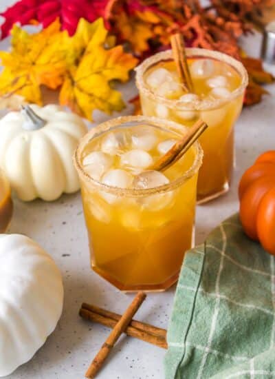 Two pumpkin spice cocktails with white pumpkin, and cinnamon sticks.