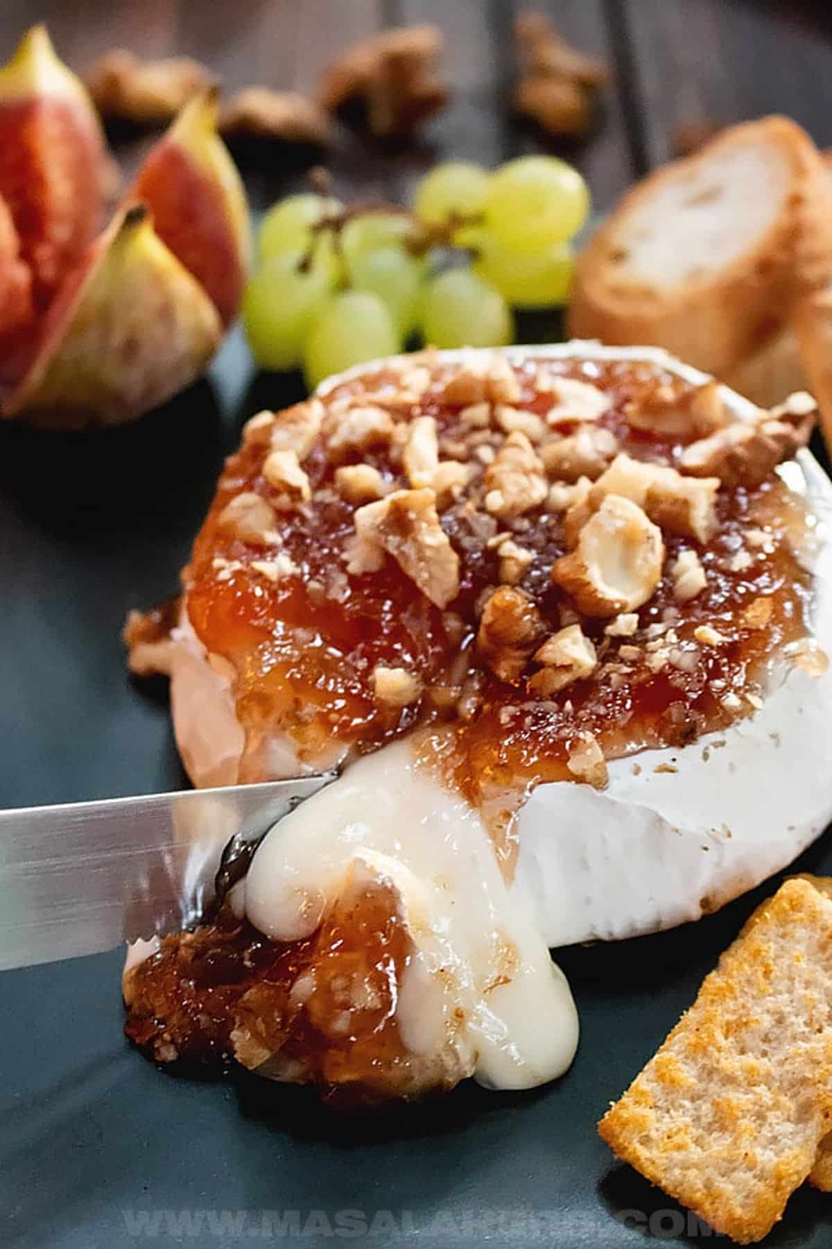 Side image of Baked Brie with Fig Jam with a knife cutting into it.