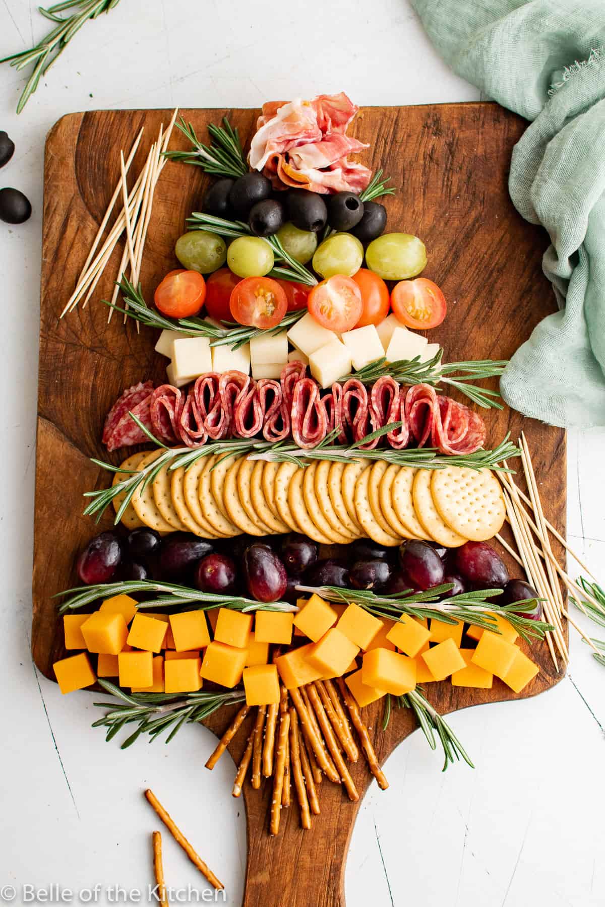 Overhead picture of Christmas Tree Charcuterie Board served on a dark wooden board with a green cloth. 