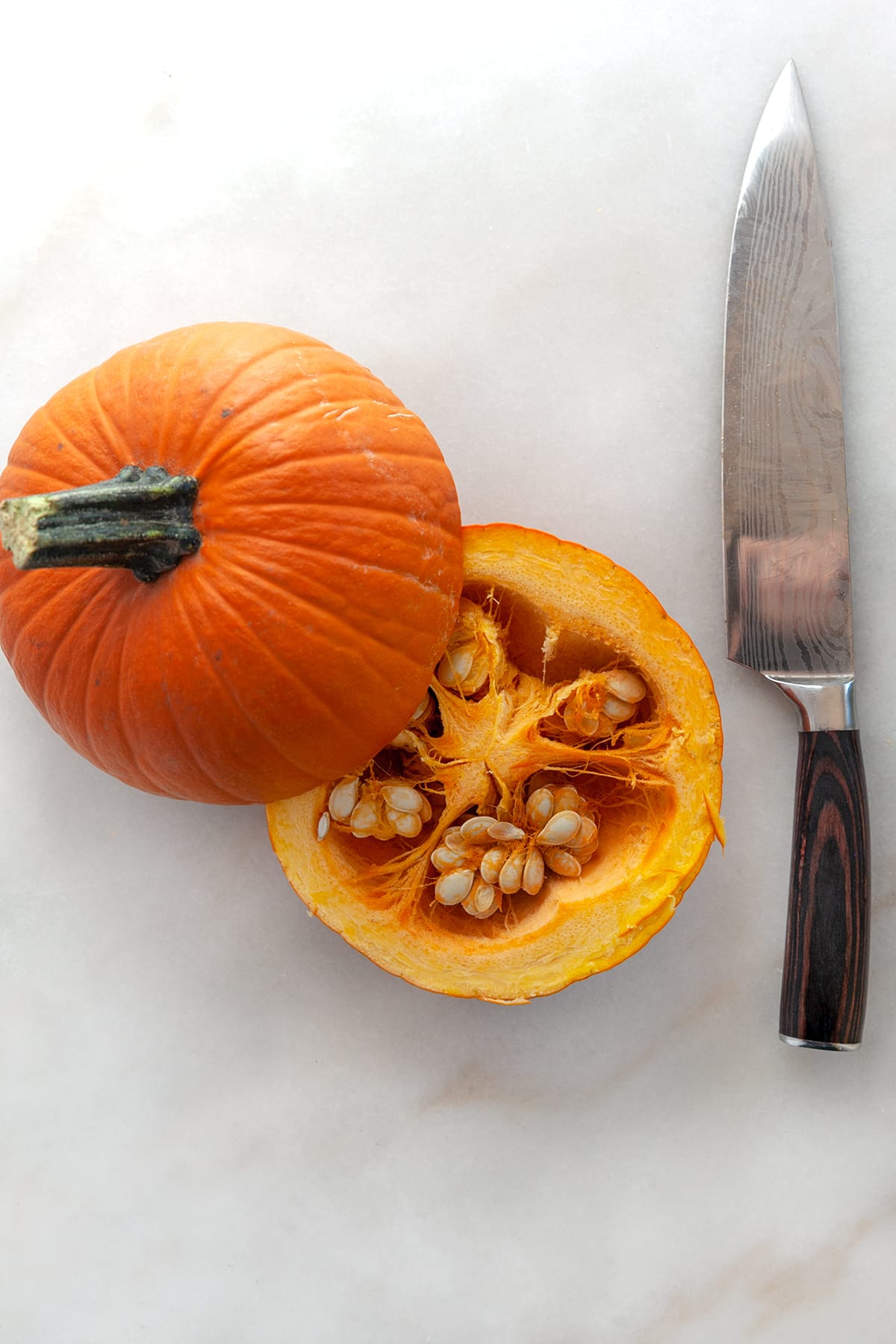 A halved pumpkin with a knife at the side. 