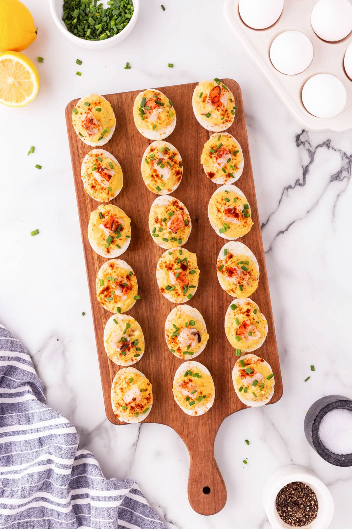 Three rows of deviled eggs on a board for serving. 