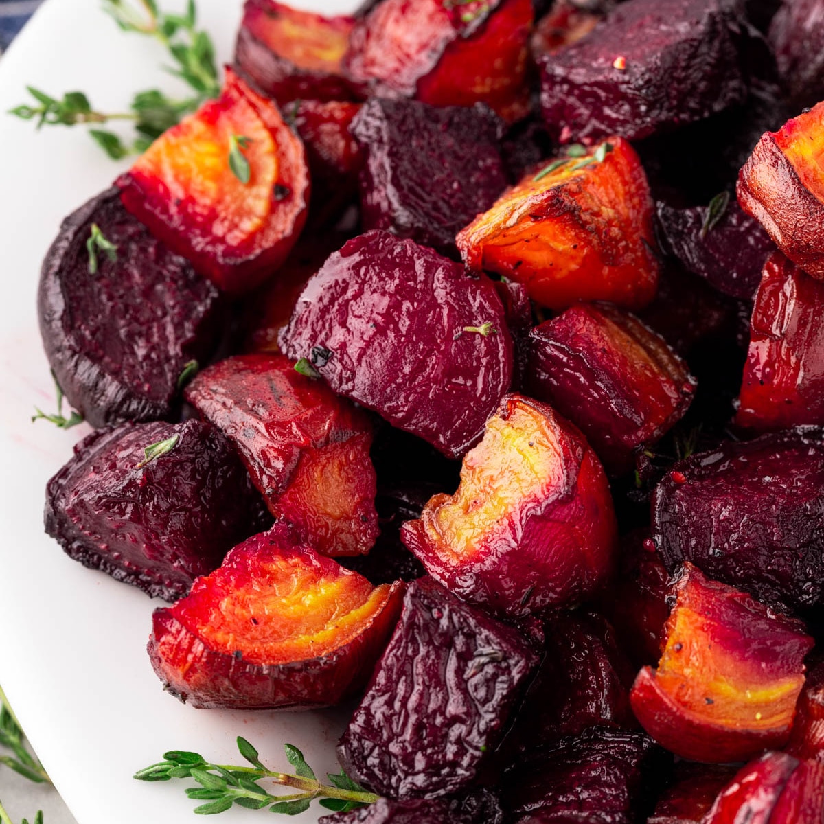 Square picture of roasted beets, yellow and red on a white platter. 