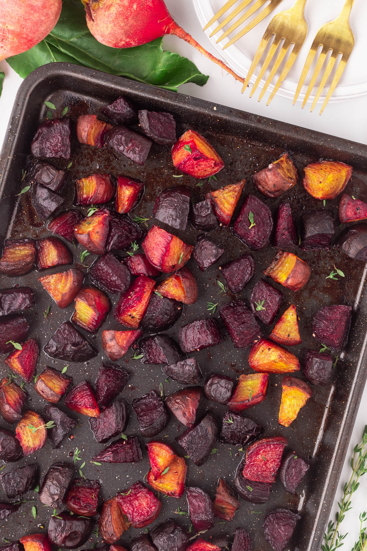 Close-up roasted beets on a dark baking sheet. 