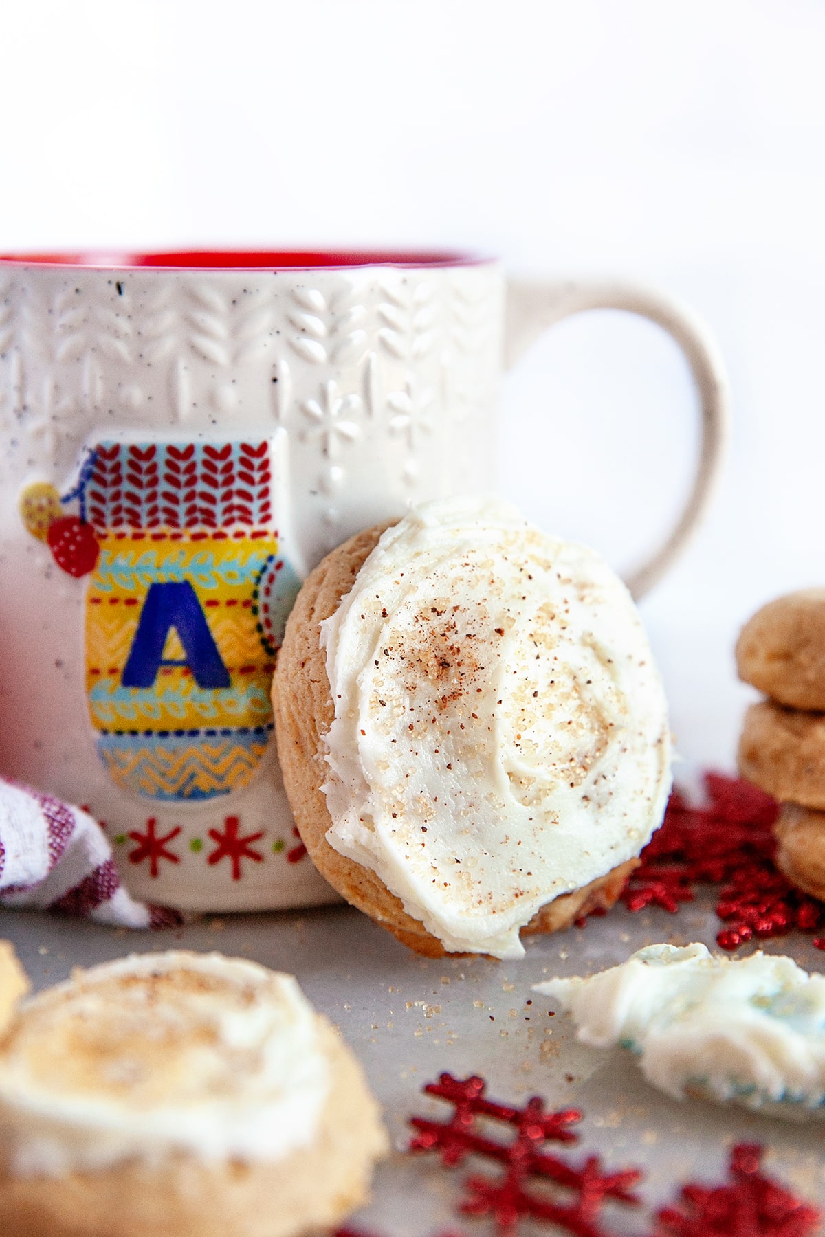 Close-up of a cookie leaning against a mug with a mitten on it that has an A!