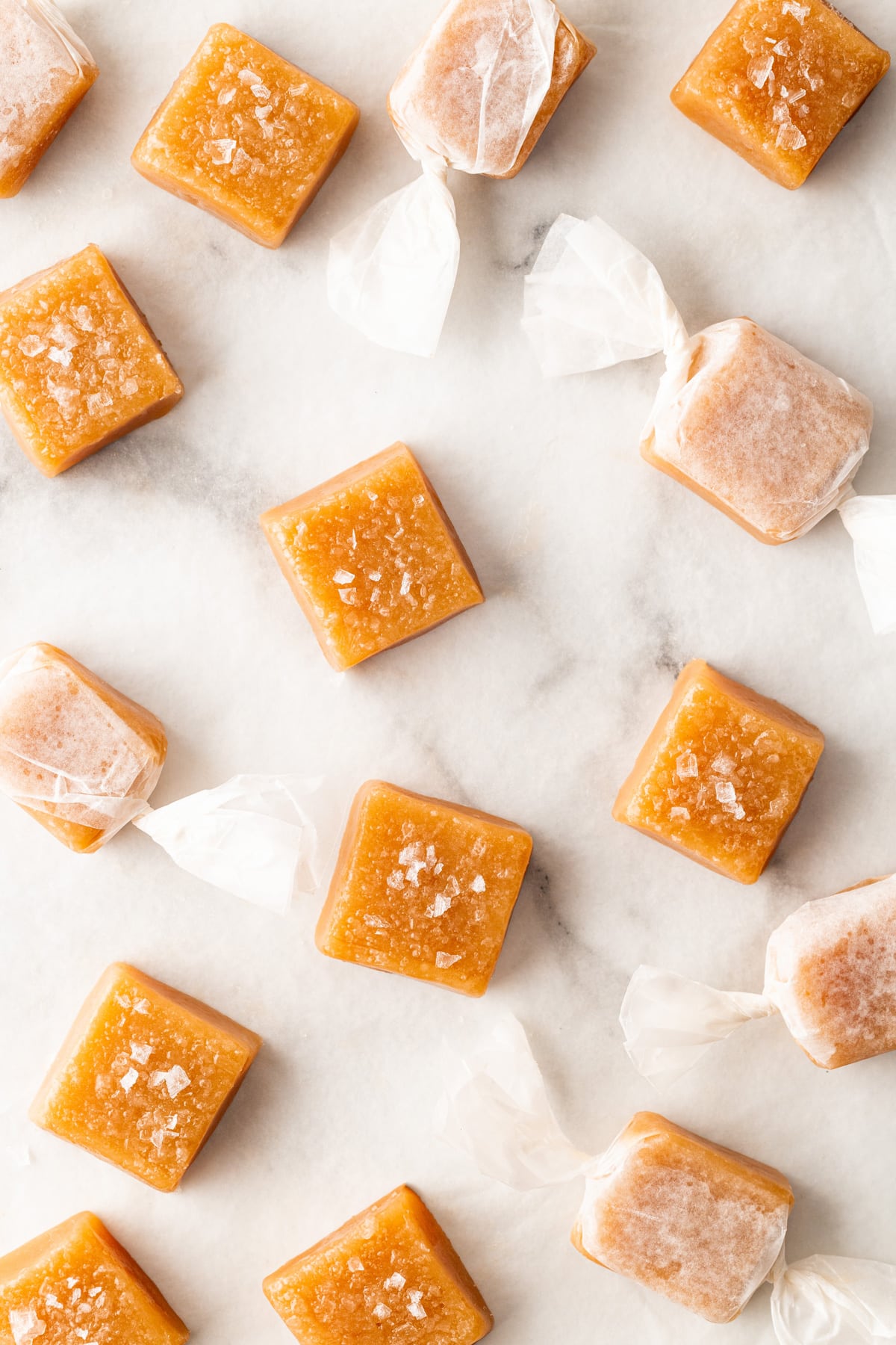 Overhead shot of salted caramels, some wrapped in wax paper. 