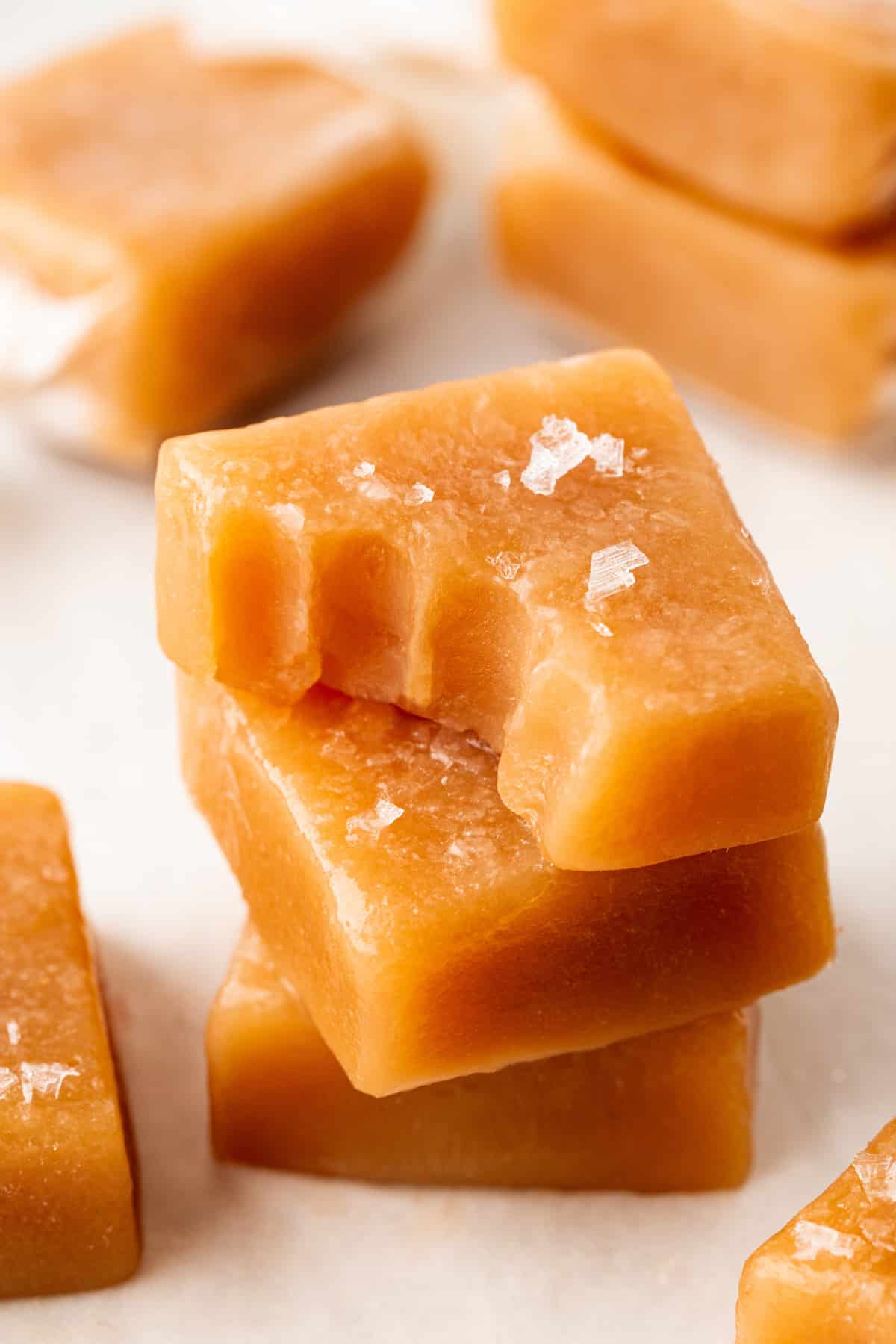 Close-up photo of stacked caramels with the top one having a bite taken. 