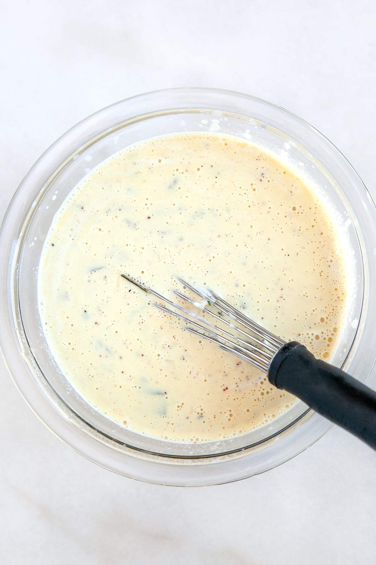 Cream sauce in a bowl with a whisk. 